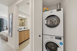 Una habitación de hotel moderna con cama, un baño con espejo y una lavadora y secadora apiladas.