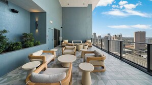 Een terras op het dak met zitplaatsen buiten, uitzicht over de stad en een modern design.