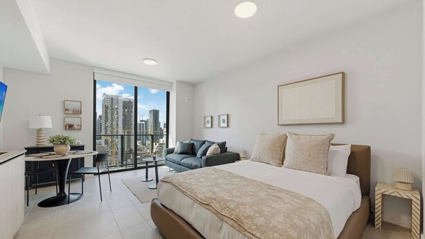 Een moderne hotelkamer met een groot bed, een bureau, een sofa en uitzicht op de stad.