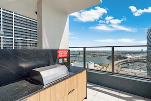 Una cocina moderna con una parrilla, vistas a un río y un rascacielos al fondo.