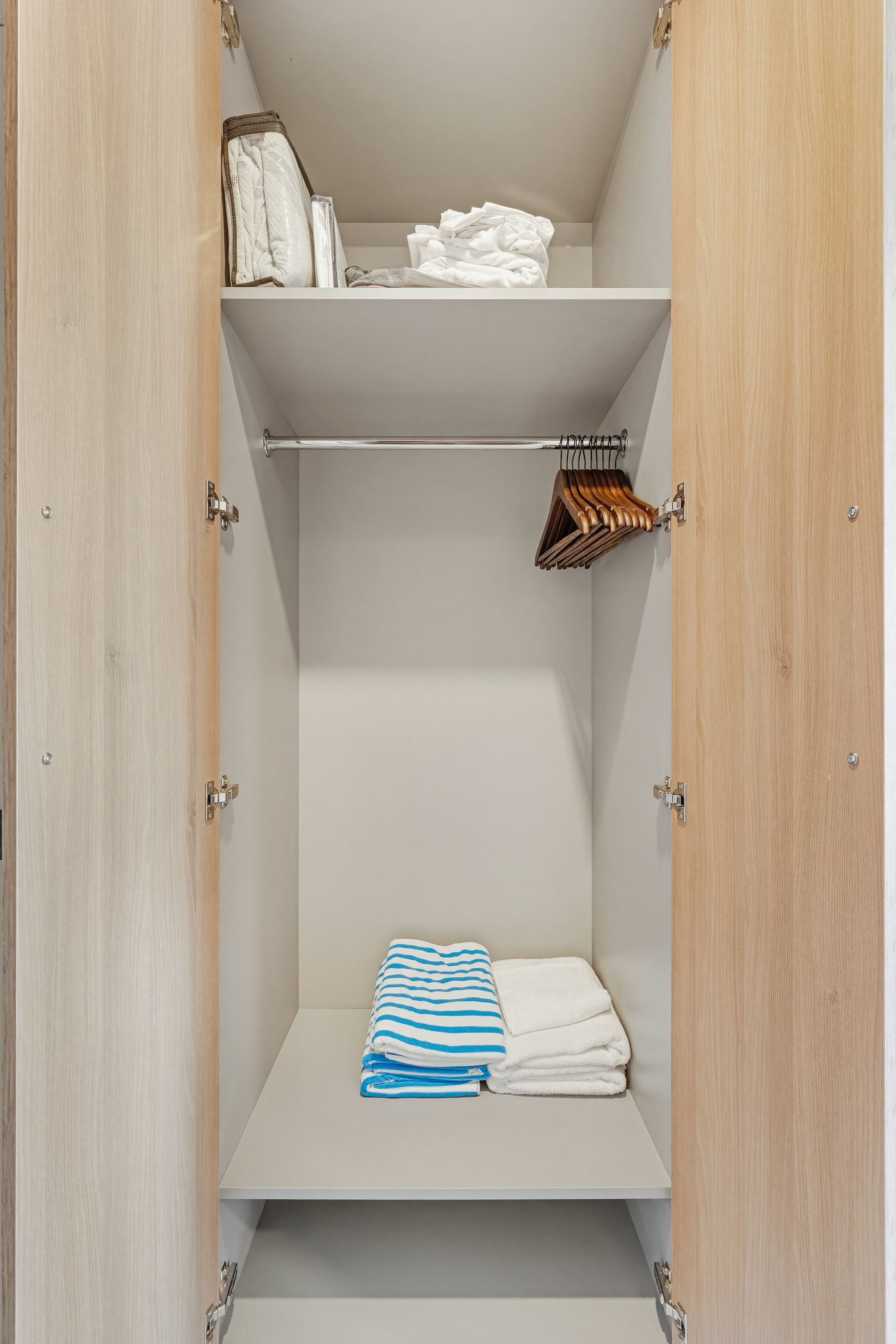 Ein begehbarer Kleiderschrank mit Regalen, einer Kleiderstange und einem gefalteten Handtuch.