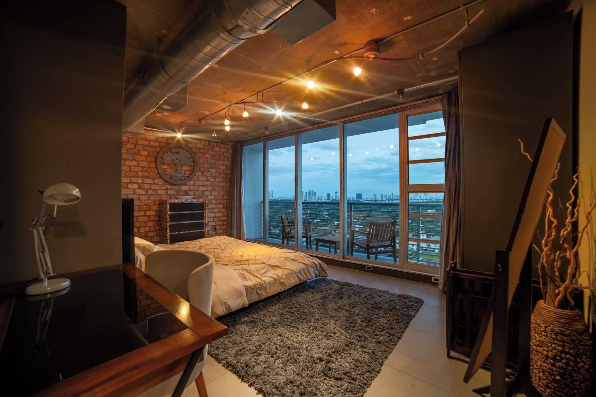 Ein Schlafzimmer mit großem Fenster, einem Bett, einem Schreibtisch und einem Stuhl.
