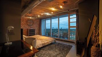 Ein Schlafzimmer mit großem Fenster, einem Bett, einem Schreibtisch und einem Stuhl.