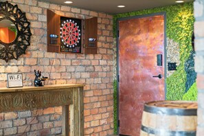 Un muro de ladrillo con un dardo, una puerta y una barra de madera con un cartel de Wi-Fi.