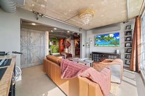 Uma sala de estar moderna com um sofá grande, uma televisão e um candelabro.