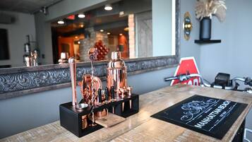 Uma área de bar com utensílios de cobre e um porta-copos preto com o texto 'Manhattan Beach'.