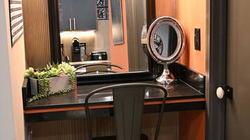 A compact bathroom with a mirror, a small sink, and a chair.