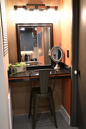 Une petite salle de bain avec un miroir, un petit lavabo et une chaise.