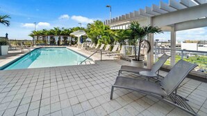 A rooftop pool area with lounge chairs and a pergola. - Midtown Rouge- Condo With City Views, Pool & Gym (Miami)