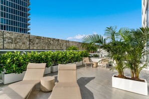 A rooftop terrace with outdoor seating, planters, and a view of a modern building. - Sea Escape- Private Sun Deck, Beachfront and Views (Miami Beach)