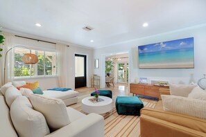 A modern living room with a sofa, coffee table, and a painting of a beach.