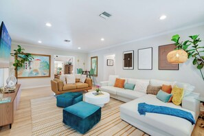 A modern living room with a sofa, armchairs, a coffee table, and a dining area.