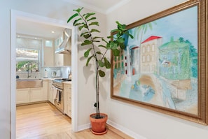 A kitchen with a potted plant, a painting, and a view into another room. - Garden Grove, 3BR Miami Home With Private Pool (Miami)