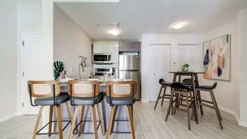 Una cocina moderna con comedor, que incluye una isla de cocina, taburetes de bar y una pequeña mesa con sillas.