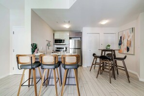 Una cocina moderna con comedor, que incluye una isla de cocina, taburetes de bar y una pequeña mesa con sillas.