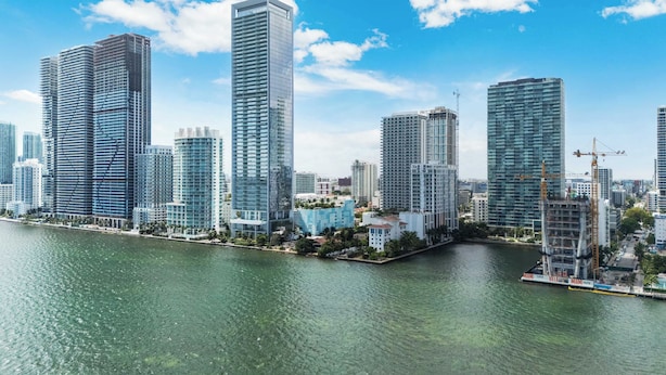 A waterfront cityscape with high-rise buildings, a clear sky, and a calm river. - Edgewater Pad- Balcony, Parking and Prime Location (Miami)