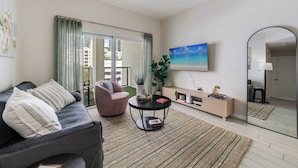 A modern living room with a sofa, armchair, round coffee table, and a large mirror. - Edgewater Pad- Balcony, Parking and Prime Location (Miami)