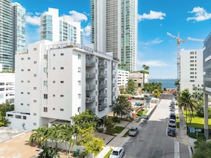 Una zona residenziale moderna in città, con edifici alti, cielo sereno e una strada con auto parcheggiate.