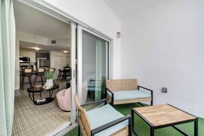 A modern living area with a sliding glass door leading to a kitchen, a small wooden table, and two wicker sofas. - Edgewater Pad Balcony, Parking and Prime Location (Miami)