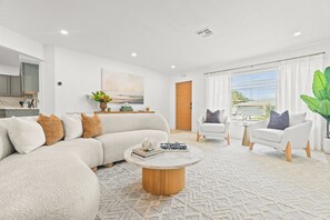 Ein modernes Wohnzimmer mit einem Ecksofa, einem Couchtisch und zwei Sessel.