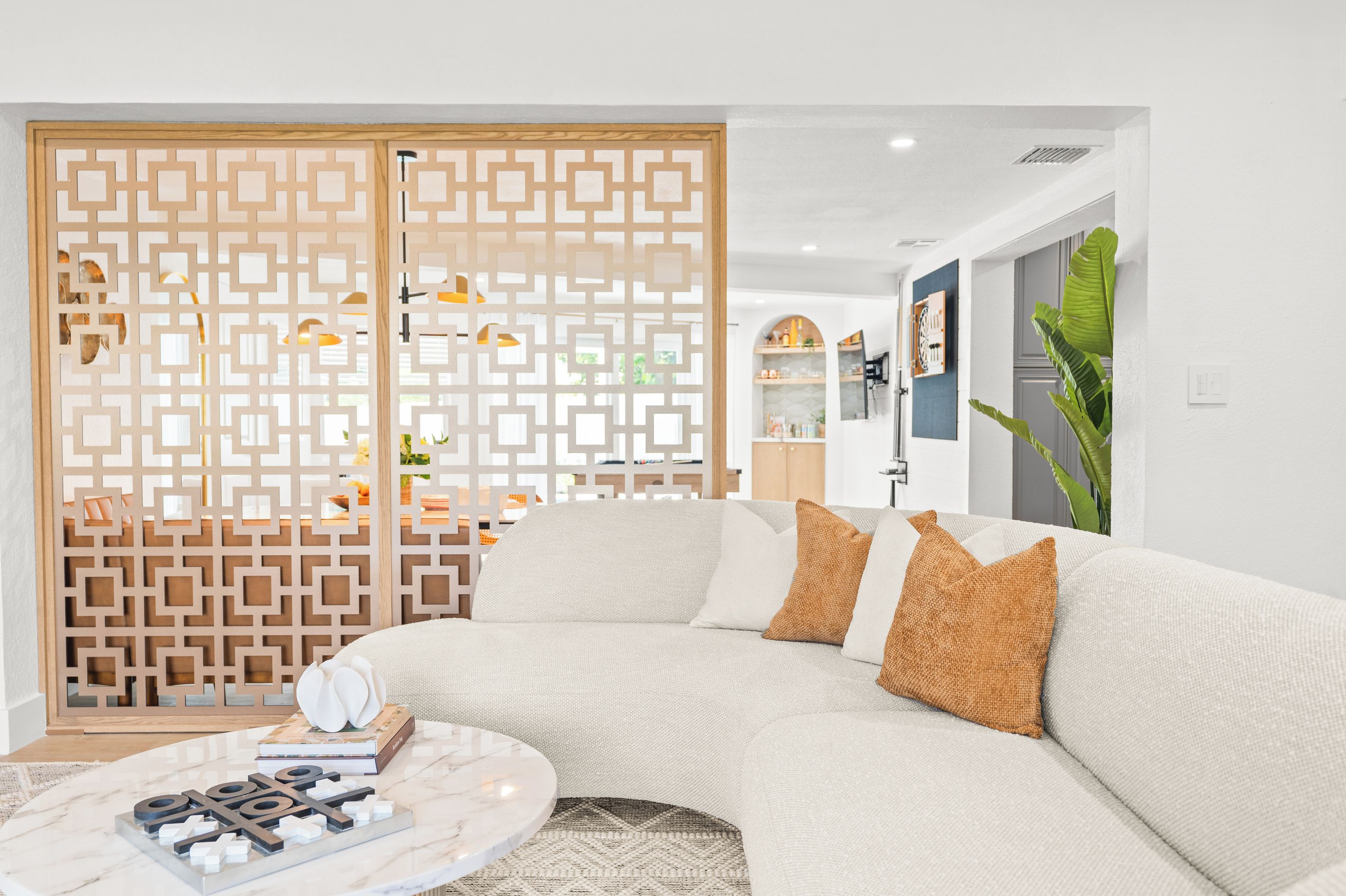 A modern living room with a sectional sofa, a marble coffee table, and a decorative screen.
