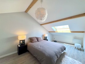 A bedroom with a sloped ceiling, a bed with a grey duvet, two bedside lamps, a fluffy white hanging light fixture, and a skylight. - Maison 8p. Aix-les-Bains Piscine (Aix-les-Bains)