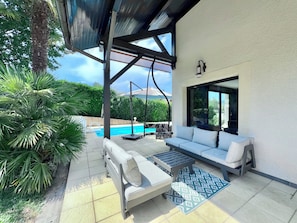 A covered outdoor seating area with a pool, a sofa, and a table. - Maison 8p. Aix-les-Bains Piscine (Aix-les-Bains)