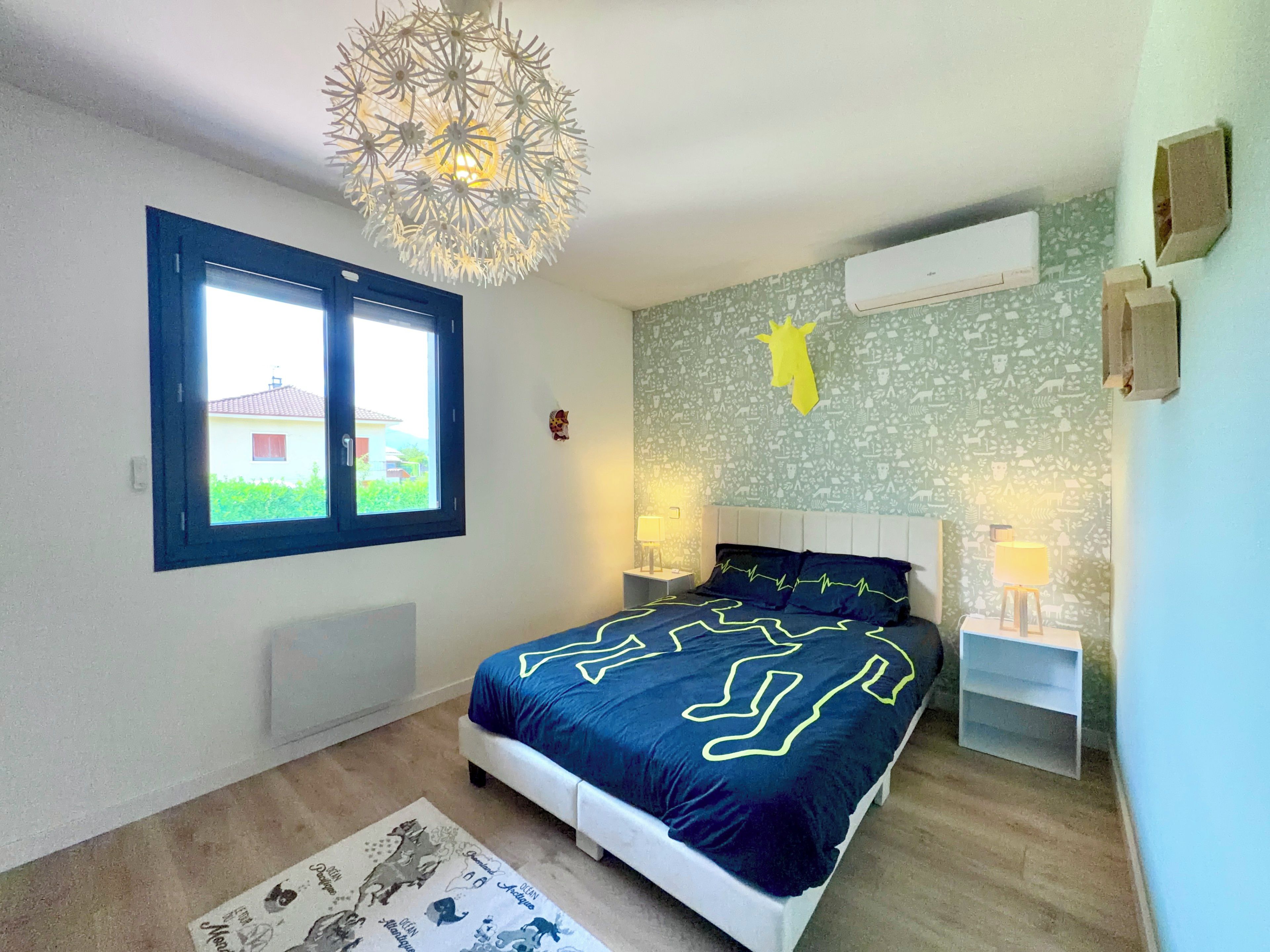 Ein Schlafzimmer mit einem Bett, Nachttischen, einem Fenster und einer Wand-Klimaanlage.