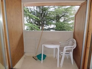 A small balcony with a white table and chair, a broom, and a green dustpan. - 200m from ski lifts, 4th floor, balcony, tv, 23m², Brides Les Bains (Brides-les-Bains)