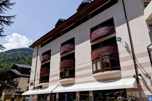 A multi-story hotel with balconies, a mountain backdrop, and a clear sky. - 200m from ski lifts, 4th floor, balcony, tv, 23m², Brides Les Bains (Brides-les-Bains)