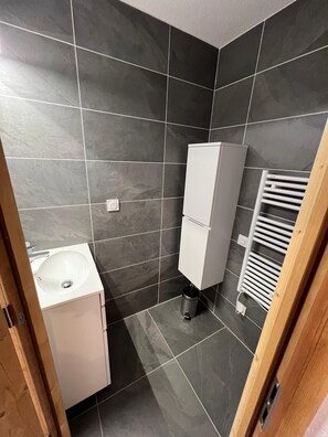 Ein Badezimmer mit einem weißen Waschbecken, einem Schrank und einem weißen Handtuchhalter.