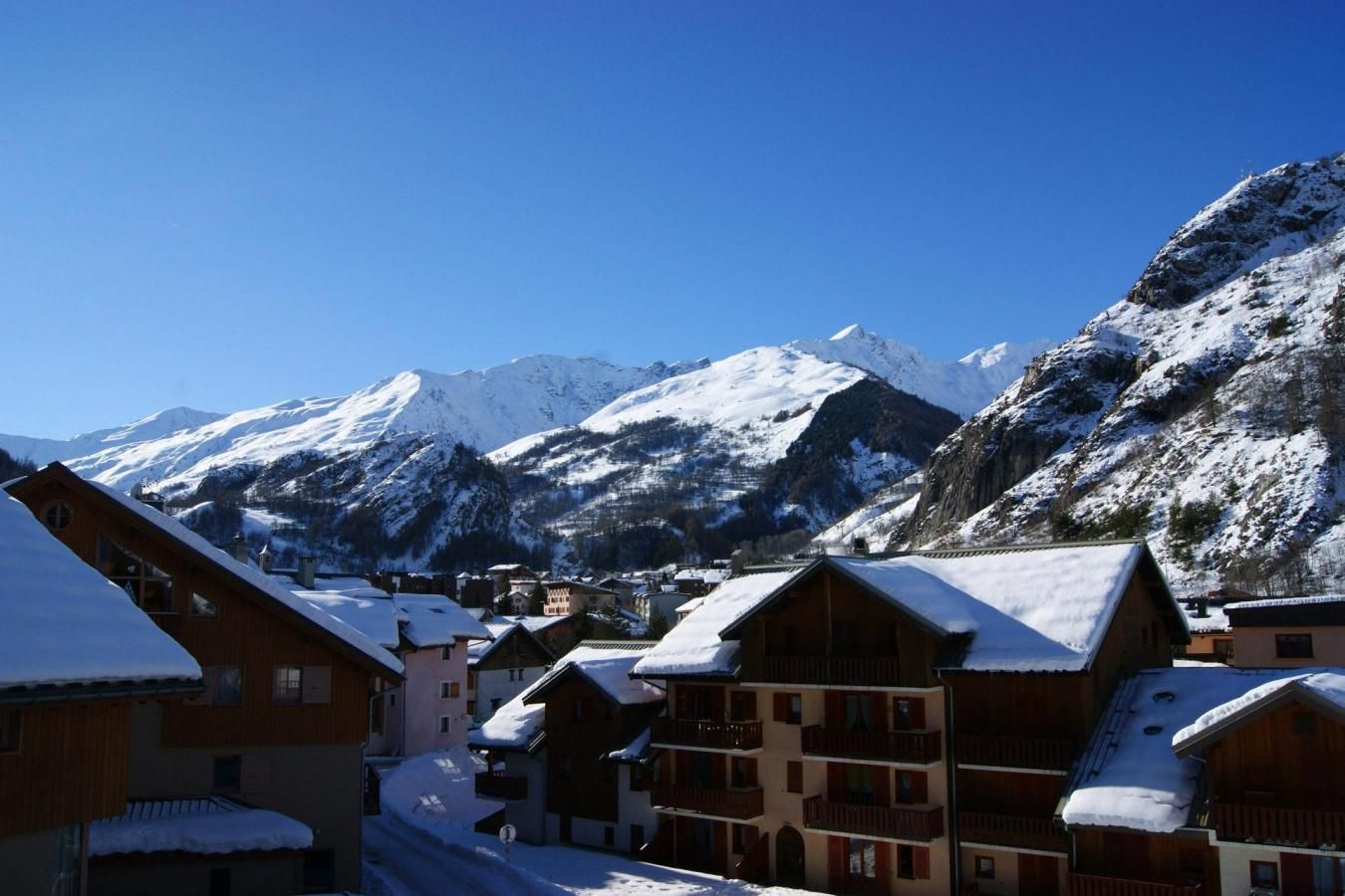 A snow-covered mountain village with wooden buildings and a clear blue sky.