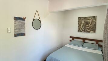 Un dormitorio con una cama, un espejo fijado a la pared, una obra de arte con estampado de cebra y una lámpara en el techo.