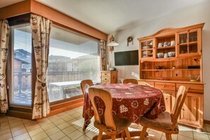A dining area with a table, chairs, a wooden cabinet with dishes, and a window with curtains. - Ground floor, balcony, tv, 32m², Les Gets (Les Gets)
