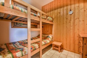 A bunk bed room with a wooden wall, a small wooden table, and a window with a view. - Ground floor, balcony, tv, 32m², Les Gets (Les Gets)