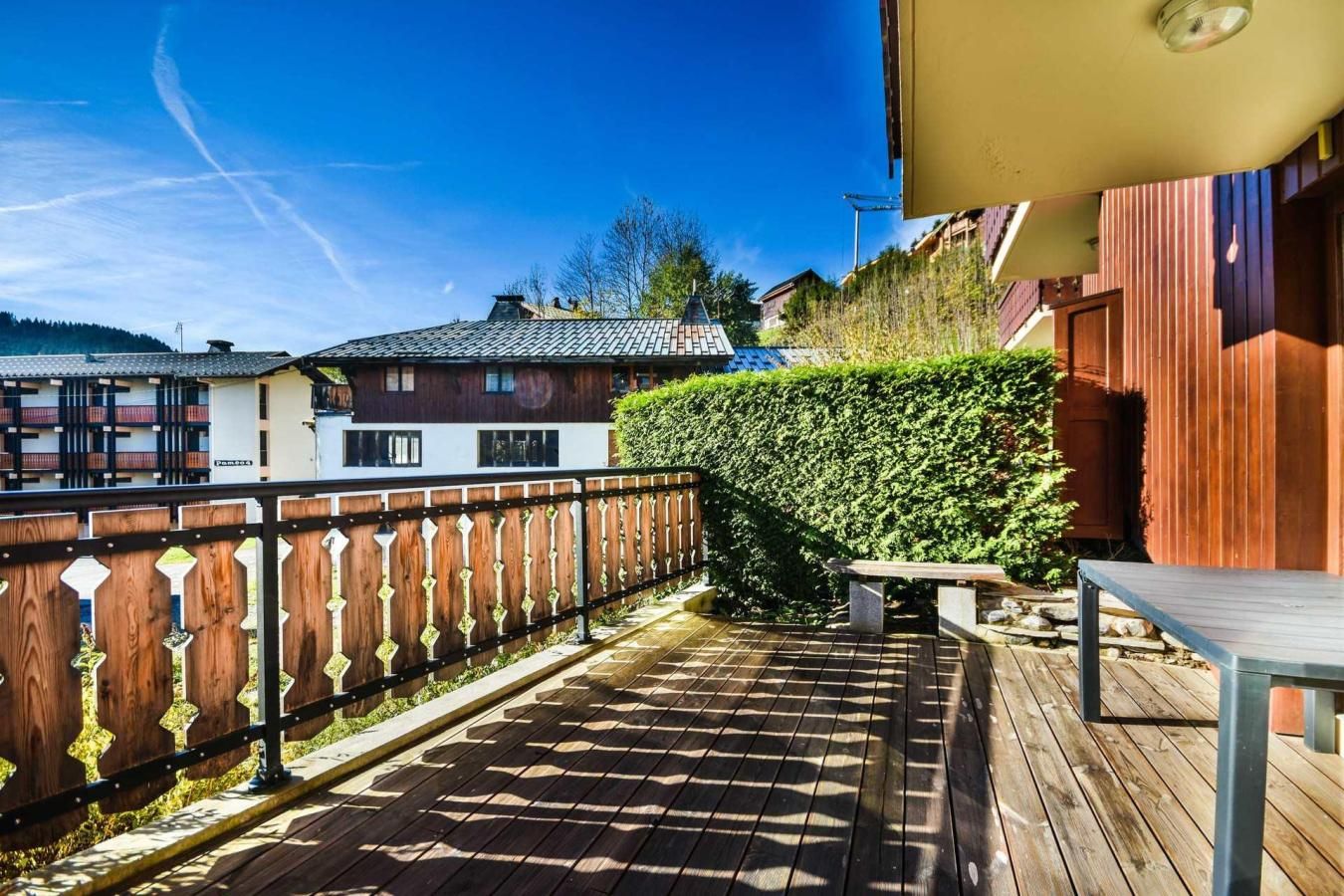 Une terrasse en bois avec un banc, une clôture en bois et une haie.