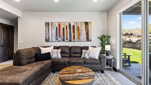 A modern living room with a sectional sofa, a coffee table, and a large abstract painting. - High West Hideaway by Avantstay Mountain-view Townhome Hot Tub + Firepit Near Park City (Heber City)