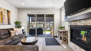 A modern living room with a sofa, coffee table, fireplace, and a view of an outdoor patio. - High West Hideaway by Avantstay Mountain-view Townhome Hot Tub + Firepit Near Park City (Heber City)