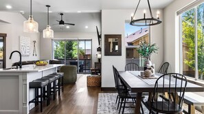 A modern kitchen with a central island, pendant lighting, and a dining area with a large table and chairs. - High West Hideaway by Avantstay Mountain-view Townhome Hot Tub + Firepit Near Park City (Heber City)