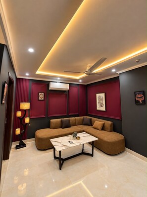 Una sala de estar moderna con un sofá modular, una mesa de centro, iluminación empotrada en el techo y un equipo de aire acondicionado.