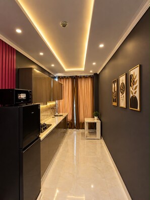 A modern kitchen with a black refrigerator, a stove, and a sink.