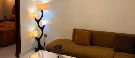 A modern living room with a ceiling fan, a marble coffee table, a sofa, and wall-mounted air conditioning.
