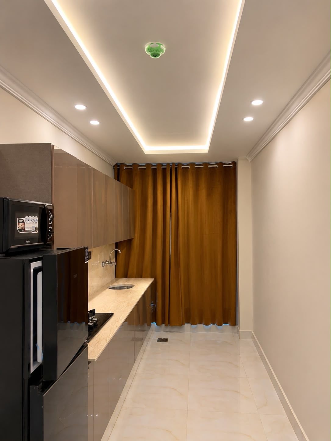 Una cocina compacta equipada con refrigerador, microondas y pileta.