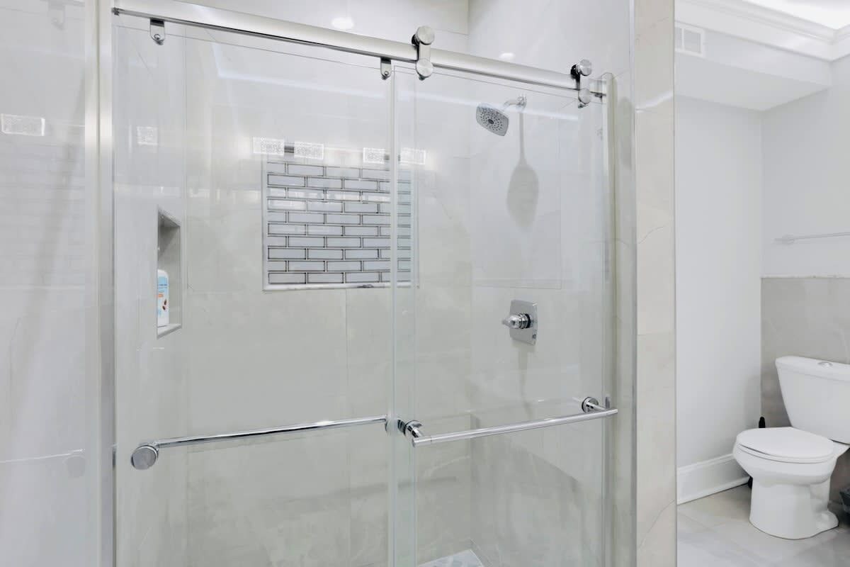 Un baño moderno con cabina de ducha de vidrio, inodoro blanco y pared con azulejos.