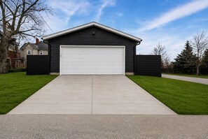 A single-story building with a garage, surrounded by a well-maintained lawn and a clear sky. - 4BR, 3.5 Baths · Spa Tub · Near Downtown Columbus (Columbus)