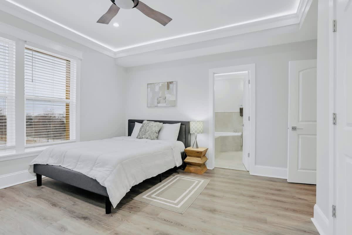 A bedroom with a bed, bedside tables, a ceiling fan, and a window with blinds.
