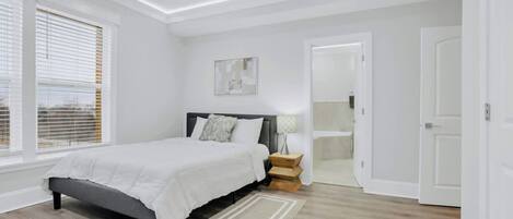 A bedroom with a bed, bedside tables, a ceiling fan, and a window with blinds.