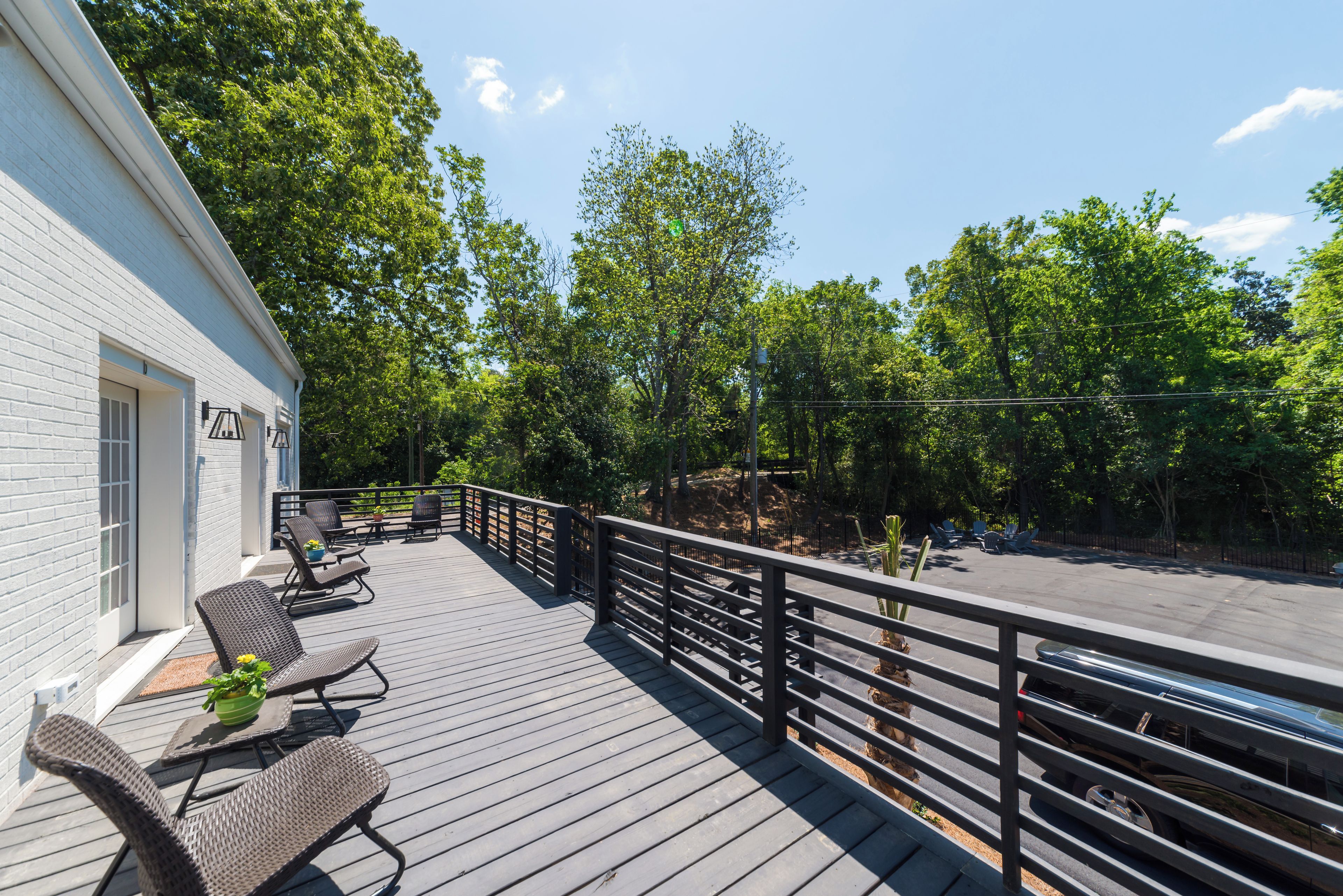 Eine Holzterrasse mit Gartenmöbeln, Geländer und Blick ins bewaldete Gebiet.