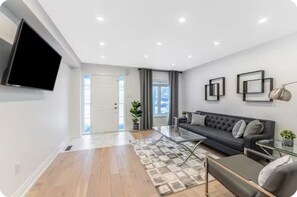 A modern living room with a sofa, a coffee table, and a flat-screen TV mounted on the wall.