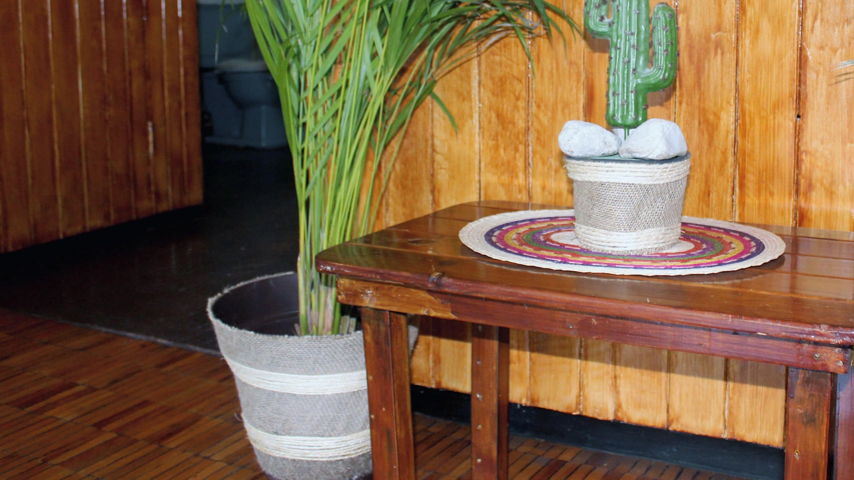 A wooden table with a woven basket and a potted plant.